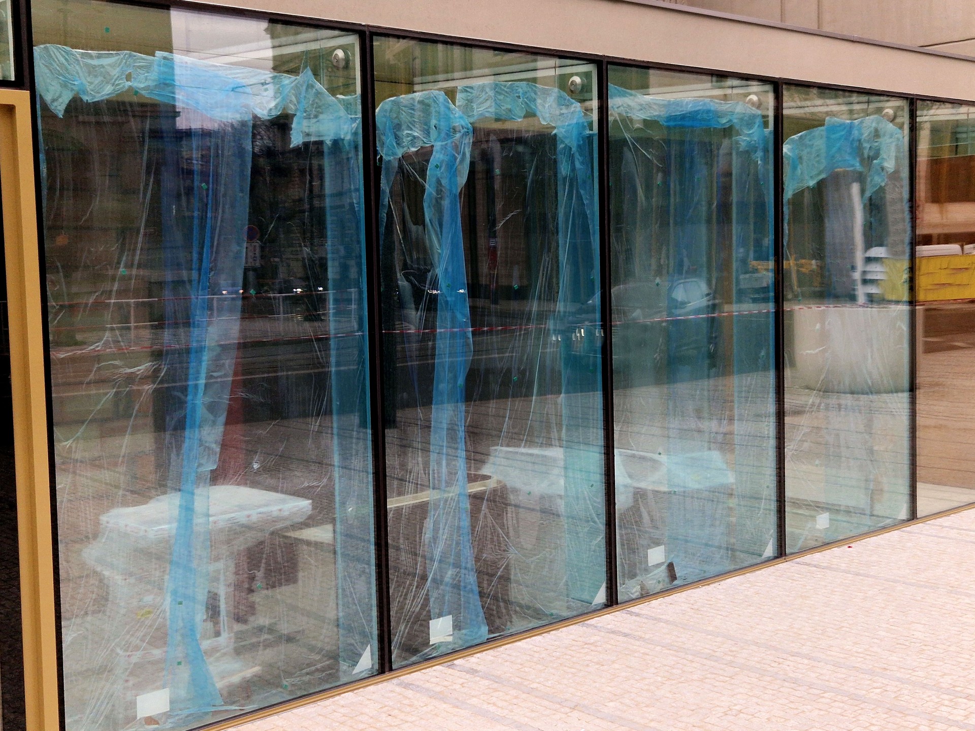 The glazier brought in new glass for shop window. There are still protective plastic films on the glass. Double and triple insulating glass with reflective UV barrier, black, blue, blanket, sticker